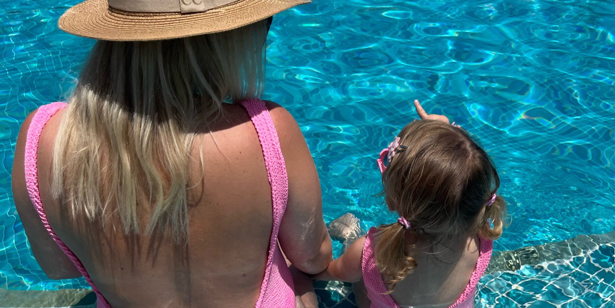 Mum and daughters wearing pink matching crinkle swimsuits on holiday