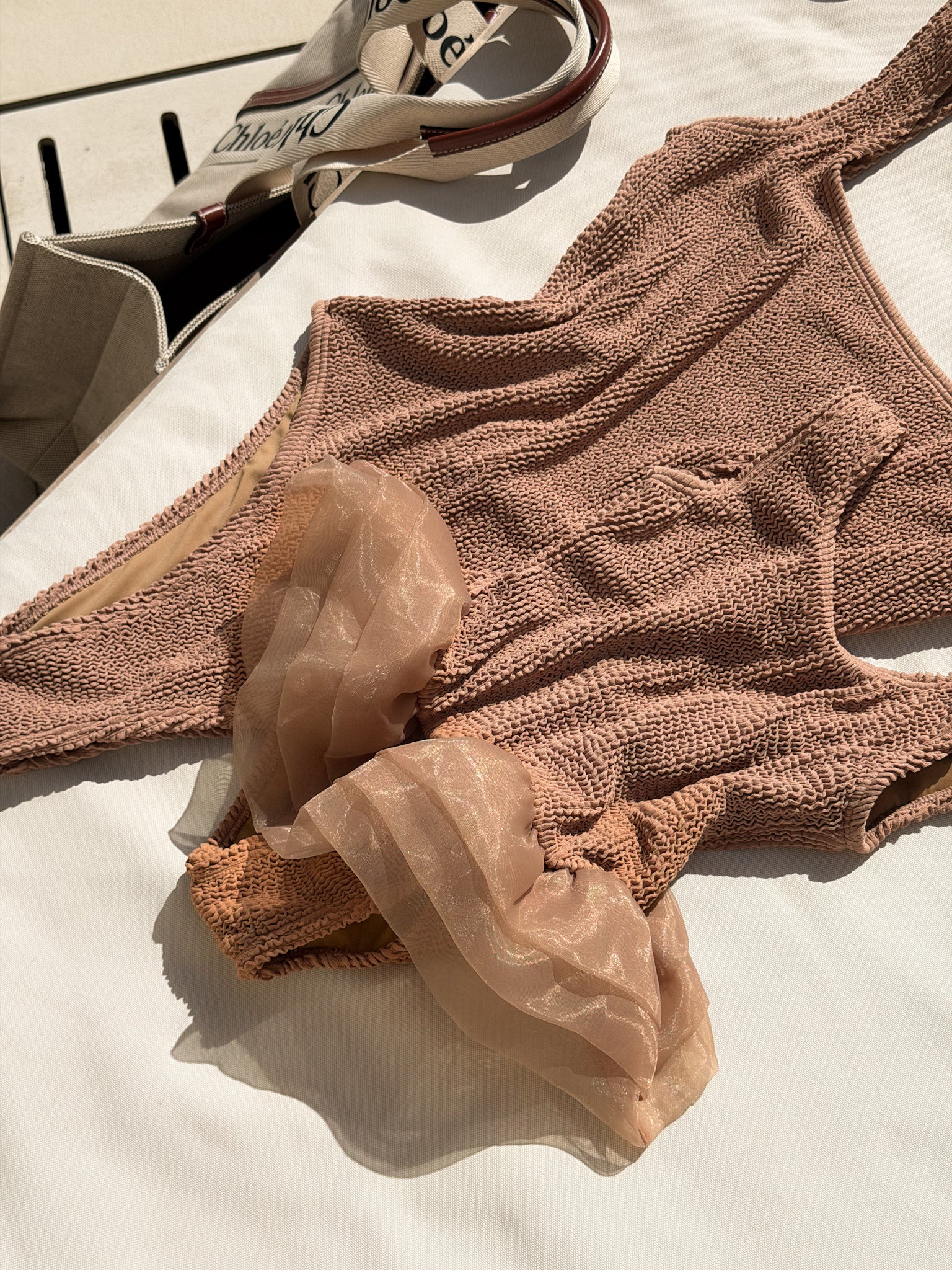 Close-up of the Muse swimsuit in mocha, showing sculpting crinkle fabric and soft ruffle 3 tier tutu detail